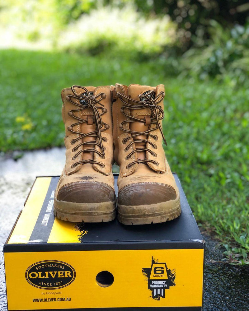 Brown boots on a yellow Oliver shoe box with grass in the background