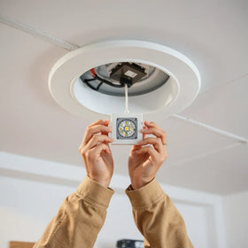 Electrician installing LED retrofit module in an existing ceiling grid with wiring connections visible